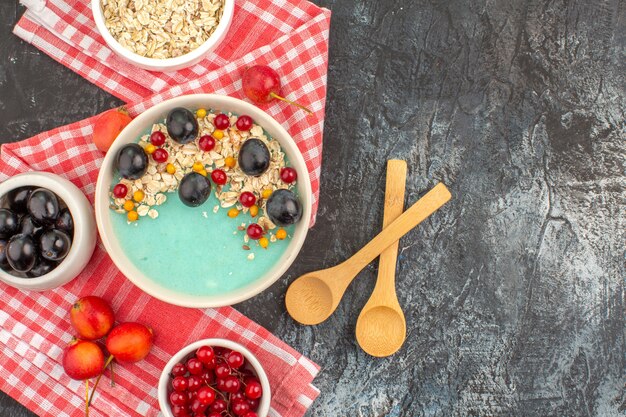 Top close-up view berries spoons bowl of grapes red currants oatmeal cherries on the tablecloth