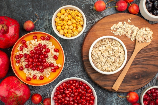 Top close-up view berries sweet candies pomegranates oatmeal spoon on the board berries candies