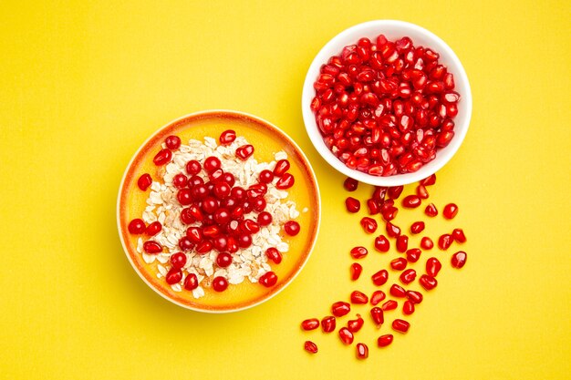 Top close-up view berries two bowls of berries oatmeal and pomegranate seeds