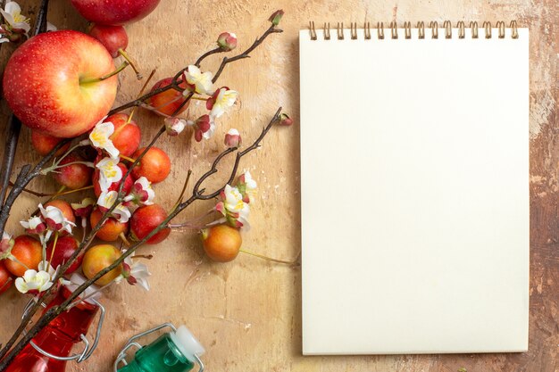 Top close-up view berries white notebook cherry apples tree branches with flowers bottles