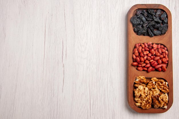 Top close-up view bowls of nuts bowls of different nuts on the right side of the white table