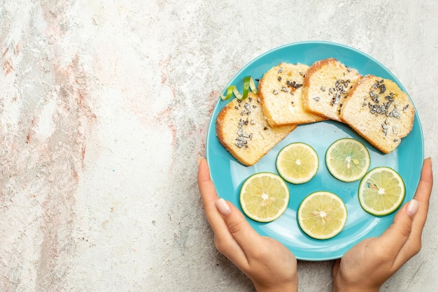 Top close-up view bread and lemon blue plate of bread and sliced lemon in hand on the white table