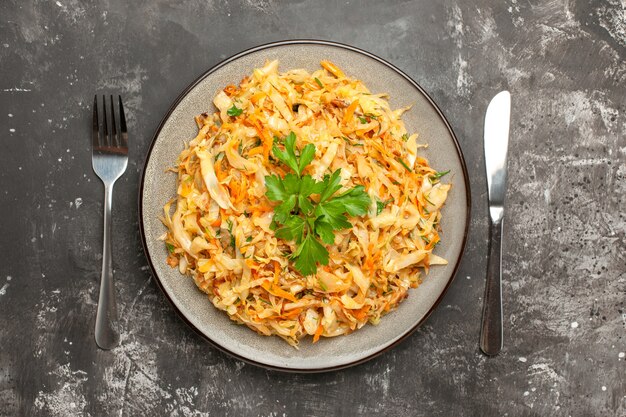 Top close-up view cabbage cabbage carrots herbs on the plate between fork and knife