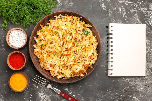 Top close-up view cabbage herbs plate of cabbage fork notebook bowls of colorful spices