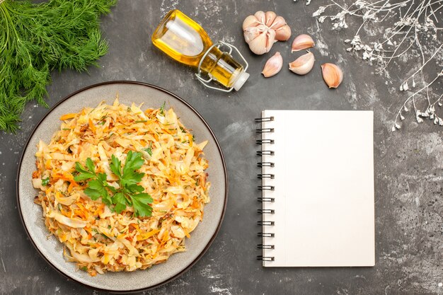 Top close-up view cabbage plate of cabbage garlic herbs bottle of oil white notebook