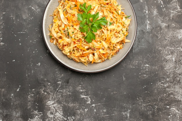 Top close-up view cabbage white plate of the appetizing carrots cabbage herbs on the table