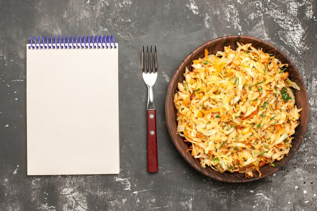 Free photo top close-up view cabbage with carrots the appetizing carrots herbs cabbage notebook fork