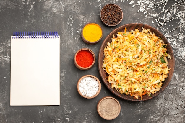 Top close-up view cabbage with carrots plate of cabbage white notebook bowls of spices