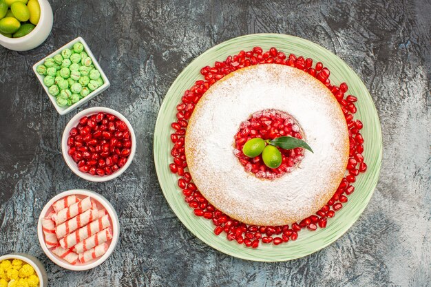 Top close-up view cake an appetizing cake bowls of citrus fruits different candies