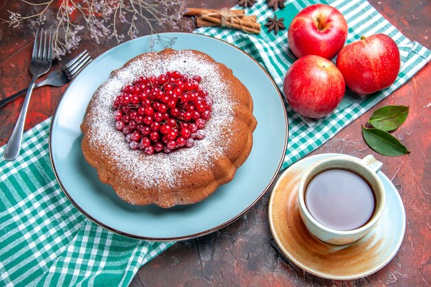 Top close-up view a cake an appetizing cake with berries apples a cup of tea forks