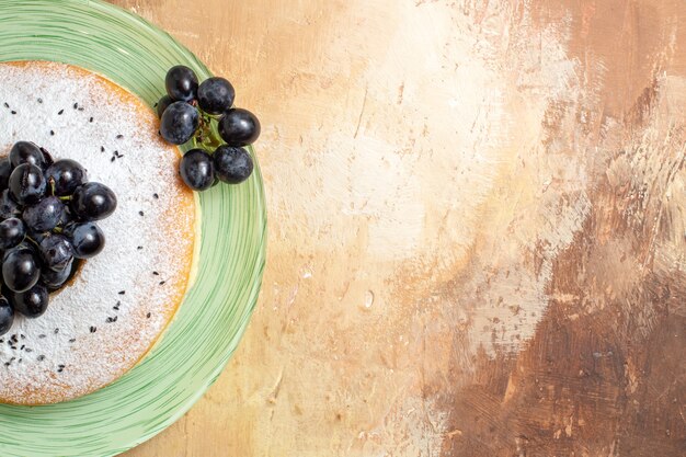 Top close-up view a cake an appetizing cake with grapes on the green plate