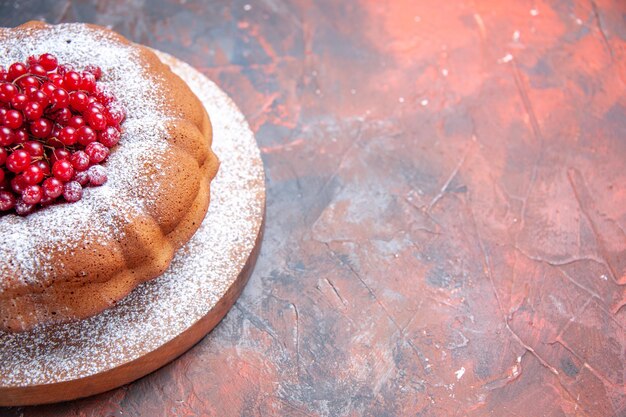 Top close-up view a cake an appetizing cake with red currants on the wooden board