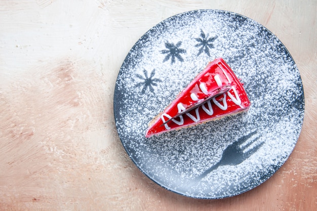 Top close-up view cake an appetizing cake with red-white creams powdered sugar on the plate