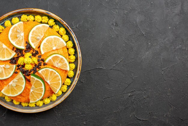 Top close-up view cake appetizing cake with slices of citrus fruit on the left side of the dark table