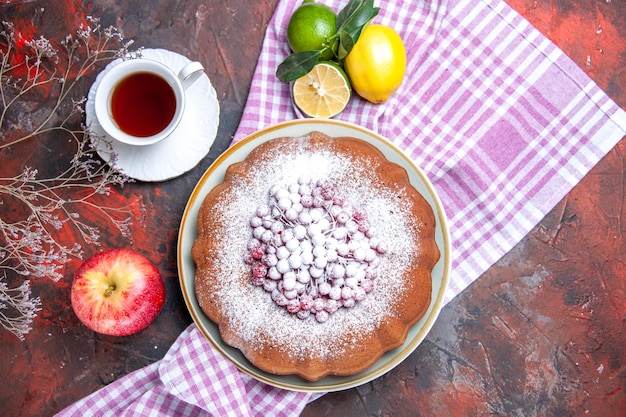 위쪽 클로즈업 보기 케이크 딸기 사과가 있는 케이크 식탁보에 감귤 차 한 잔