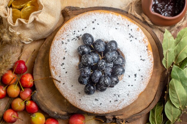 Top close-up view a cake a cake with grapes on the board berries chocolate sauce leaves