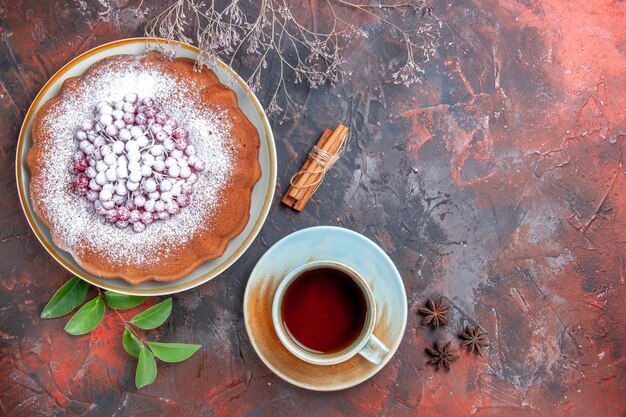 Top close-up view a cake a cake with powdered sugar star anise cinnamon a cup of tea