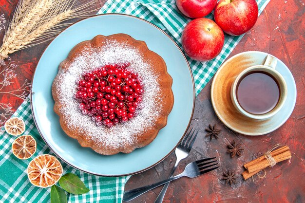 Top close-up view a cake a cup of tea cinnamon star anise forks a cake apples on the tablecloth