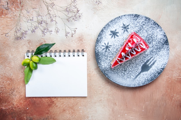 Top close-up view a cake plate of cake notebook citrus fruits