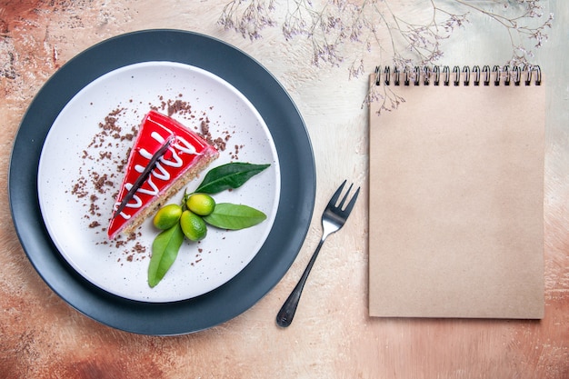 최고 근접 촬영보기 초콜릿 소스 감귤류 과일 포크 크림 노트북 케이크의 케이크 접시