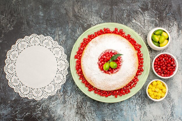 석류 시트러스 과일 사탕 레이스 냅킨이 있는 케이크 한 접시와 과자