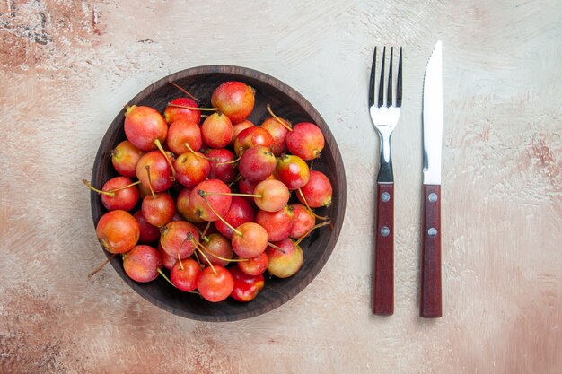 Top close-up view cherries the appetizing cherries in the bowl fork knife on the table