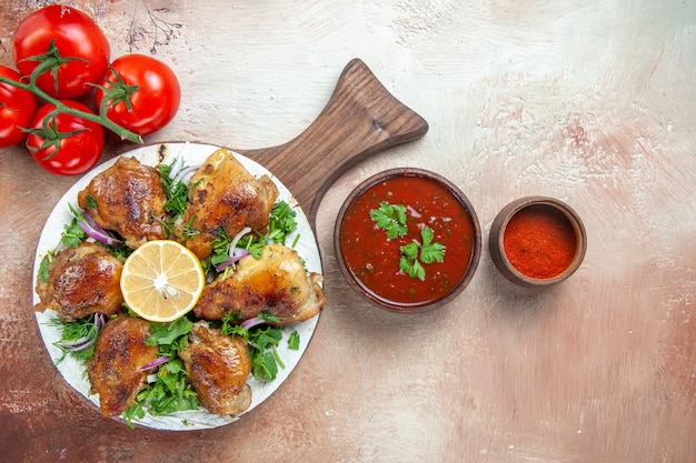 Top close-up view chicken the appetizing pieces of chicken with lemon herbs spices tomatoes sauce