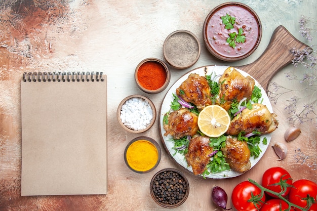 Top close-up view chicken chicken with herbs lemon tomatoes sauce spices cream notebook