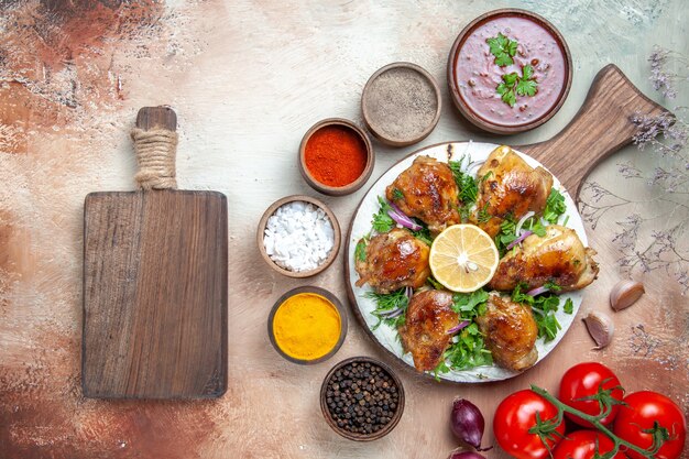 Top close-up view chicken chicken with herbs lemon tomatoes sauce spices the cutting board