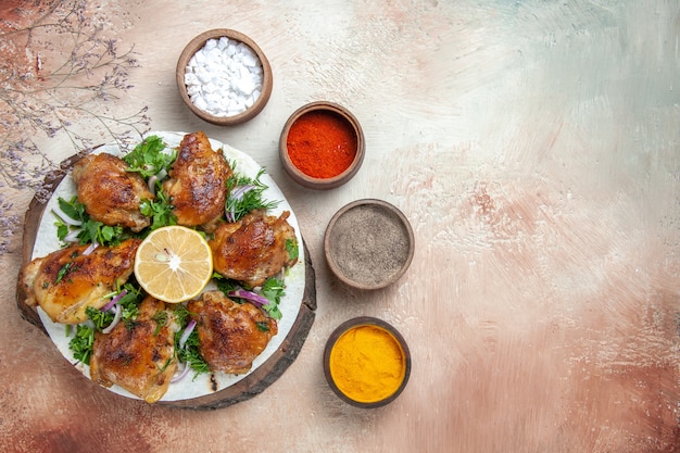 Top close-up view chicken chicken with lemon herbs on the cutting board bowls of spices