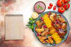 Free photo top close-up view chicken sauce chicken with potatoes pomegranate tomatoes cream notebook