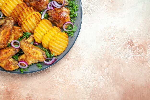 Top close-up view chicken wings the appetizing fried potatoes chicken herbs and onions