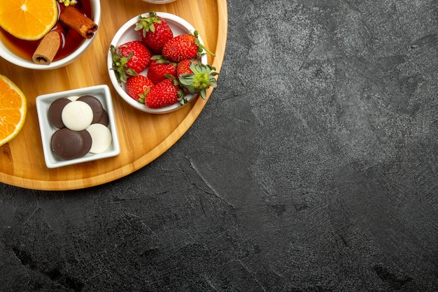 上のクローズアップビューチョコレートイチゴのチョコレートレモンボウルテーブルの左側にシナボンスティックとレモンとお茶のカップ