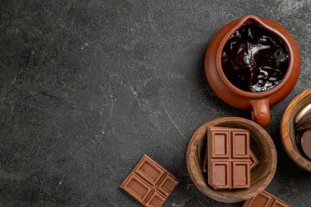 チョコレートとチョコレートソースの黒いテーブルの茶色のボウルの右側にある上部のクローズアップビューチョコレートソース