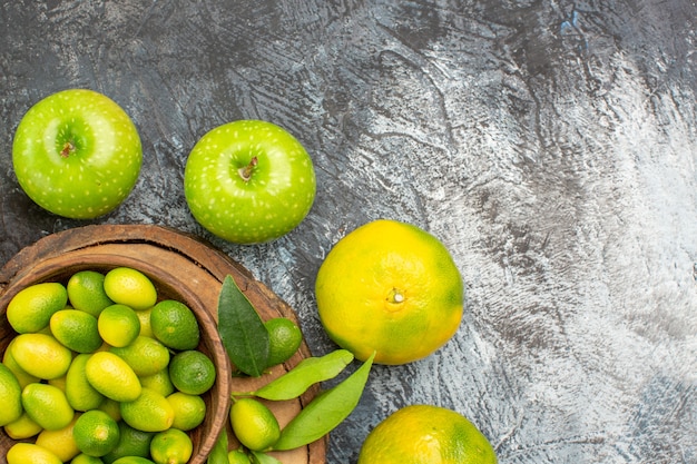 Top close-up view citrus fruits apples mandarins around the cutting board with citrus fruits