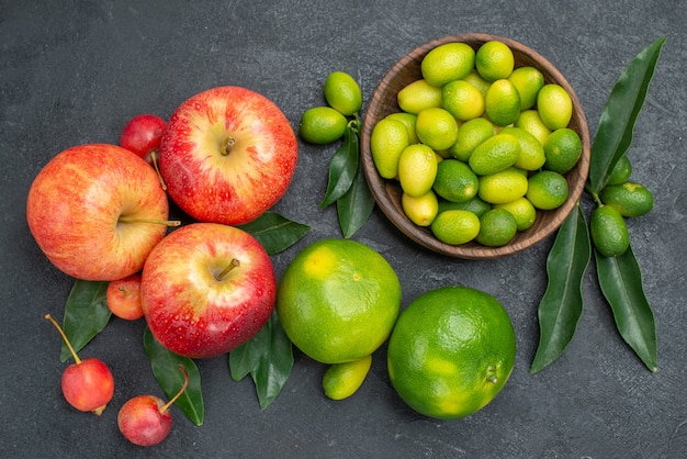 Top close-up view citrus fruits bowl of citrus fruits with leaves apples cherries mandarins