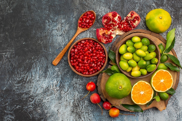 Free photo top close-up view citrus fruits bowl of pomegranate seeds spoon citrus fruits on the board