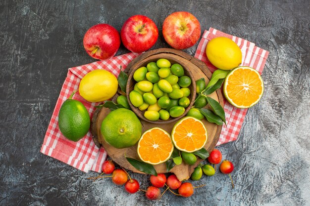 Top close-up view citrus fruits citrus fruits on the board cherries apples on the tablecloth
