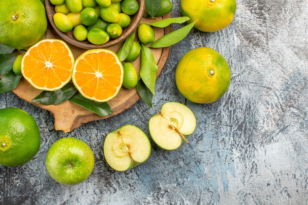 Top close-up view citrus fruits mandarins apples around the cutting board with citrus fruits