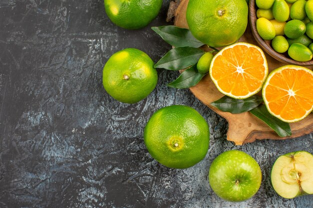 Top close-up view citrus fruits oranges mandarins green apples on the cutting board