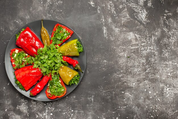 Top close-up view colorful pepper colorful peppers with herbs on the black plate