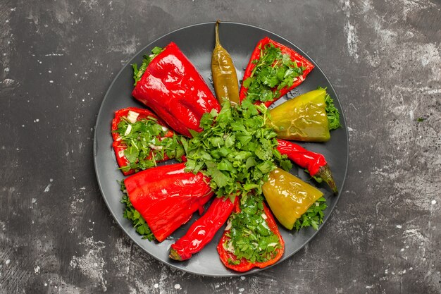 Top close-up view colorful pepper different kinds of peppers with herbs on the black plate