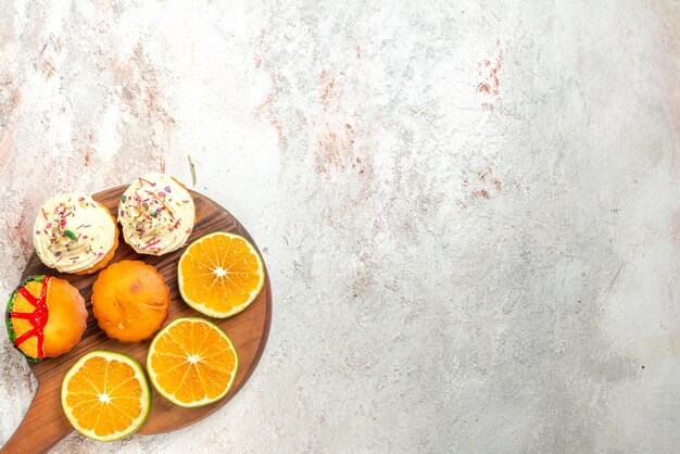 Top close-up view cookies appetizing cookies and sliced orange on the cutting board on the left side of the table