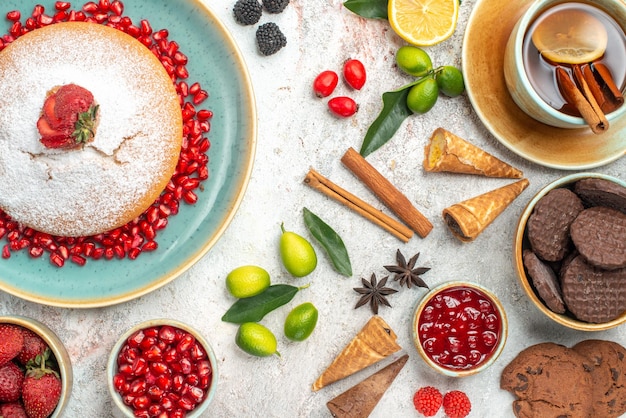 Top close-up view cookies and cake a cake cookies a cup of tea citrus fruits cinnamon sticks