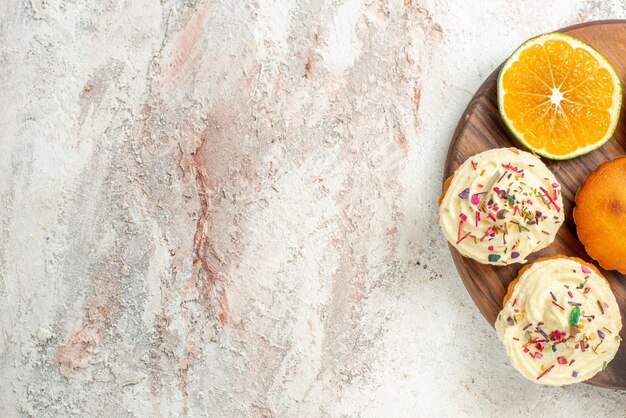 Free photo top close-up view cookies wooden cutting board with appetizing cookies and sliced orange on the table