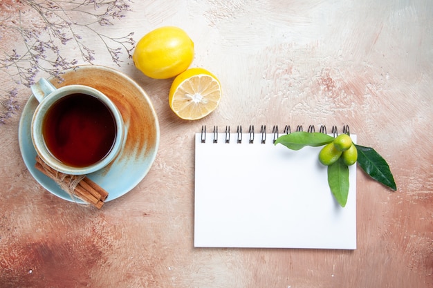 Top close-up view a cup of tea a cup of tea cinnamon lemon white notebook