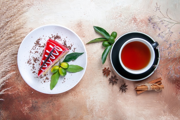 Top close-up view a cup of tea a cup of tea cinnamon sticks citrus fruits plate of cake