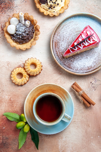 Top close-up view a cup of tea a cup of tea cupcakes cookies cinnamon cake citrus fruits