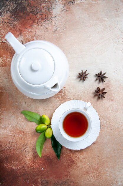 Top close-up view a cup of tea a cup of tea white teapot citrus fruits star anise