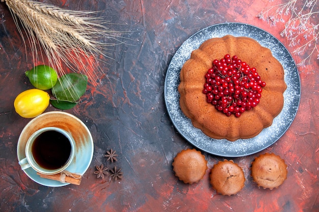 Vista ravvicinata dall'alto una tazza di tè una tazza di tè con cupcakes alla cannella torta con frutti di bosco limoni